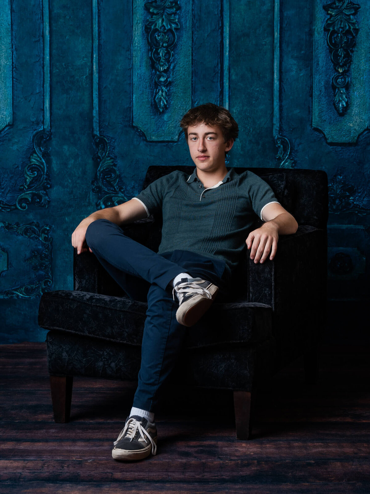 High school senior boy poses in chair for Prescott senior photos