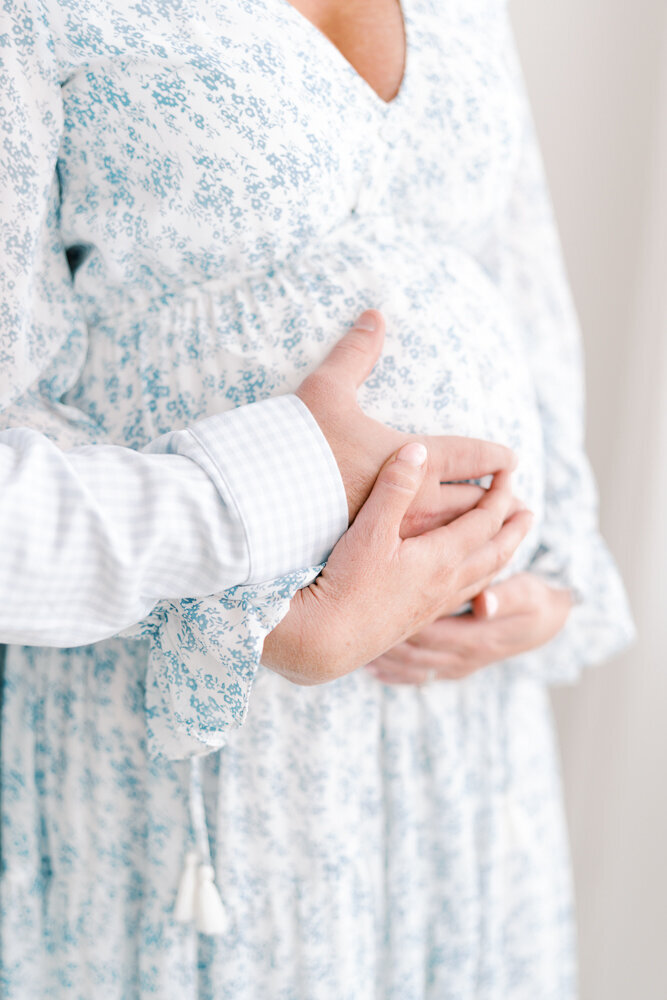 mom-and-dad-holding-pregnant-belly-blue-dress