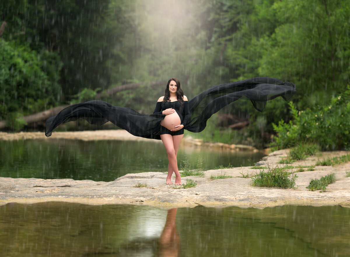 Pregnant woman wearing black flowing gown standing in the rain