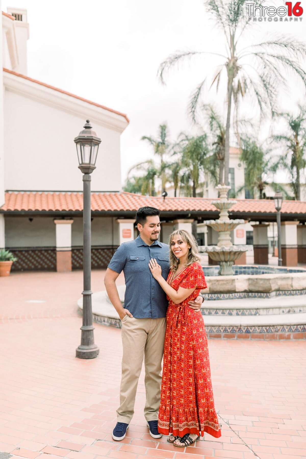 Groom to be looks at his fiance as they pose for photos