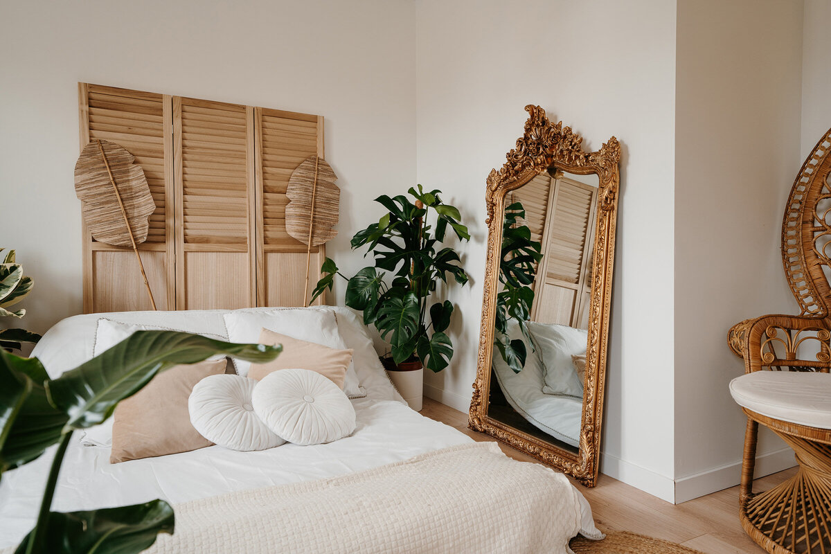 Studio photo en Vendée de Laura T Photographie. Lit et panneaux de bois et plantes ambiance exotique et grand miroir avec dorures.