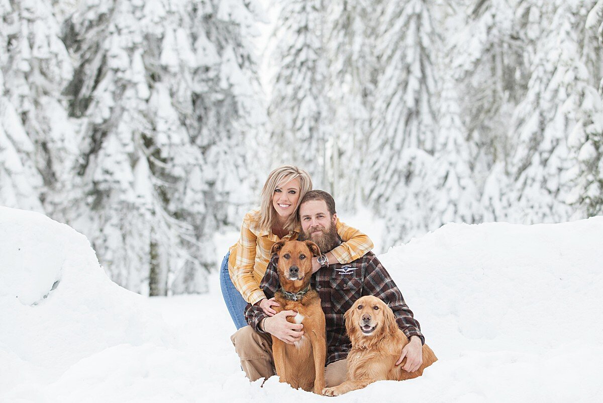 Cute couple with two dogs hugging in the snow