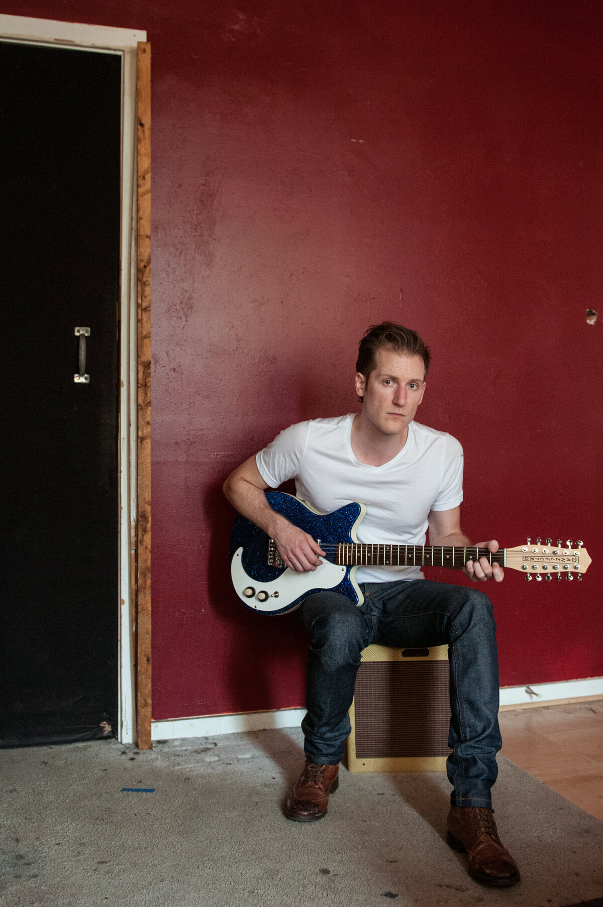 A person sitting on an amp playing an electric guitar
