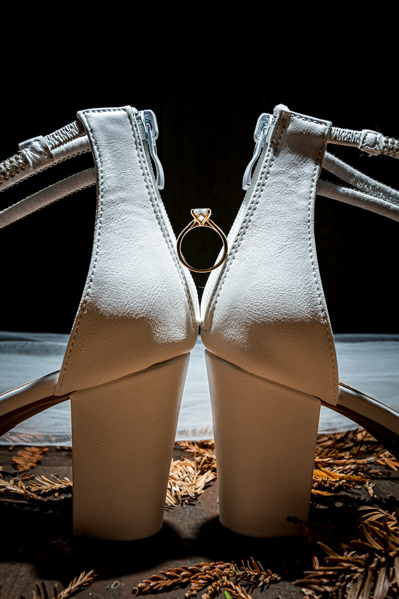 A beautifully styled detail shot of the bride’s engagement ring perfectly balanced between her wedding shoes in Ferndale, CA, capturing the elegance and charm of her special day.