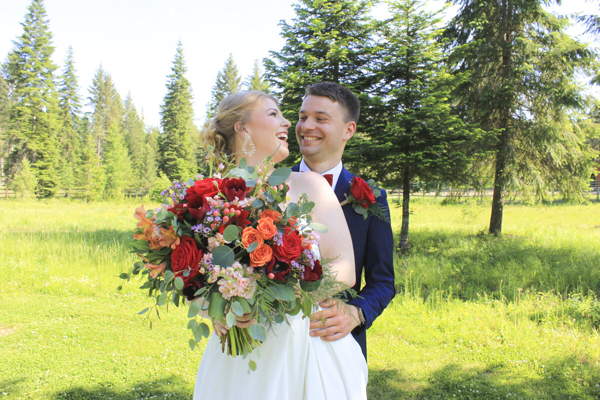Couple just married in grassy meadow  in Bayview Idaho smiling at each other