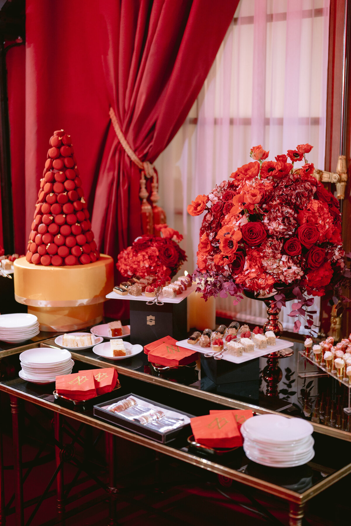 The stunning photo was captured at the iconic Shangri La Hotel & Ritz Paris Hotel in Paris, France, by the talented photographer Matteo Coltro. The sophisticated table setup showcases a tall cone of red macarons, a sumptuous bouquet of red roses, plates adorned with assorted desserts, and impeccably folded red napkins. Set against a backdrop of opulent red drapes, the scene exudes a palpable sense of luxury and celebration. Zen Film Works served as videographers capturing the behind-the-scenes magic of this elegant event.