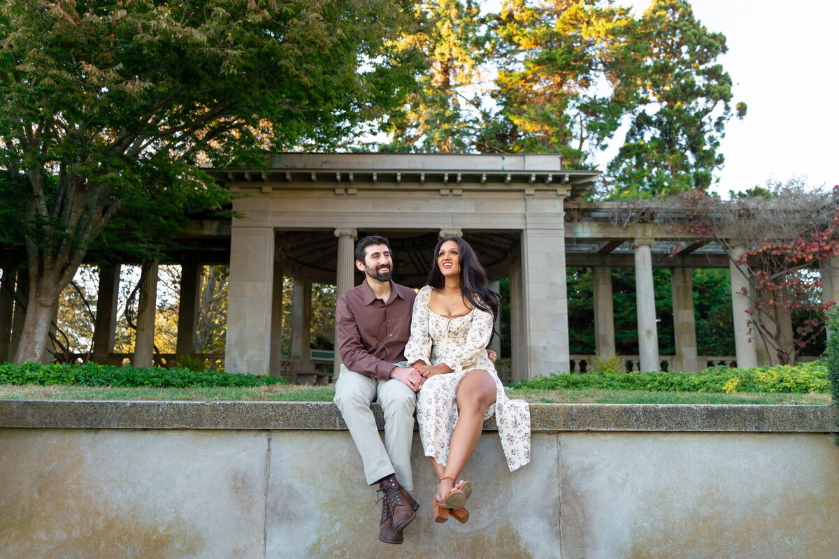 Staright mixed race couple sit next to each other iin the gardens at Harkness Memorial State Park