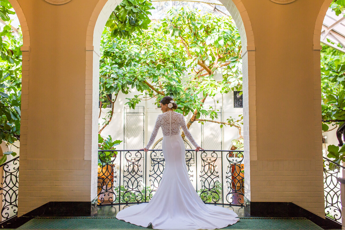 bride on the balcony of fox chapel golf club with iron rails and archway with dress spread out behind her