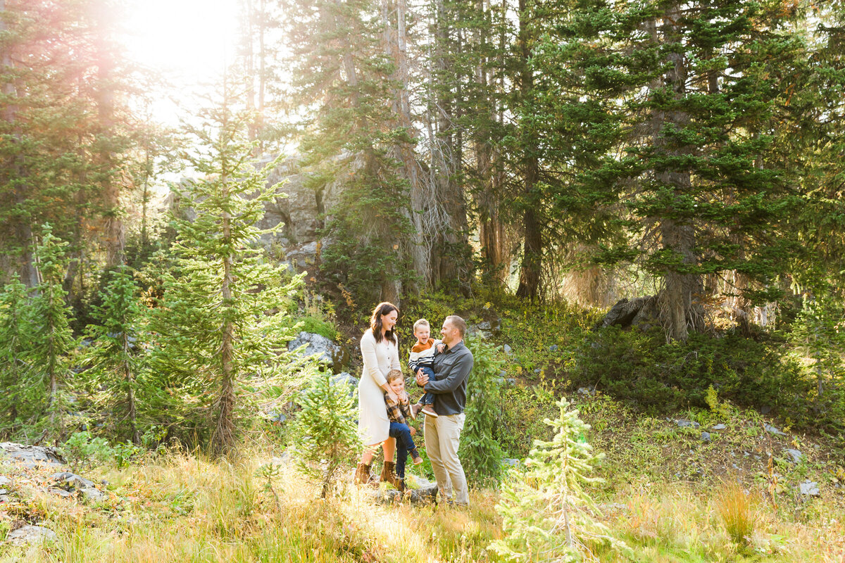 family smiling at each other in Alta Utah forest