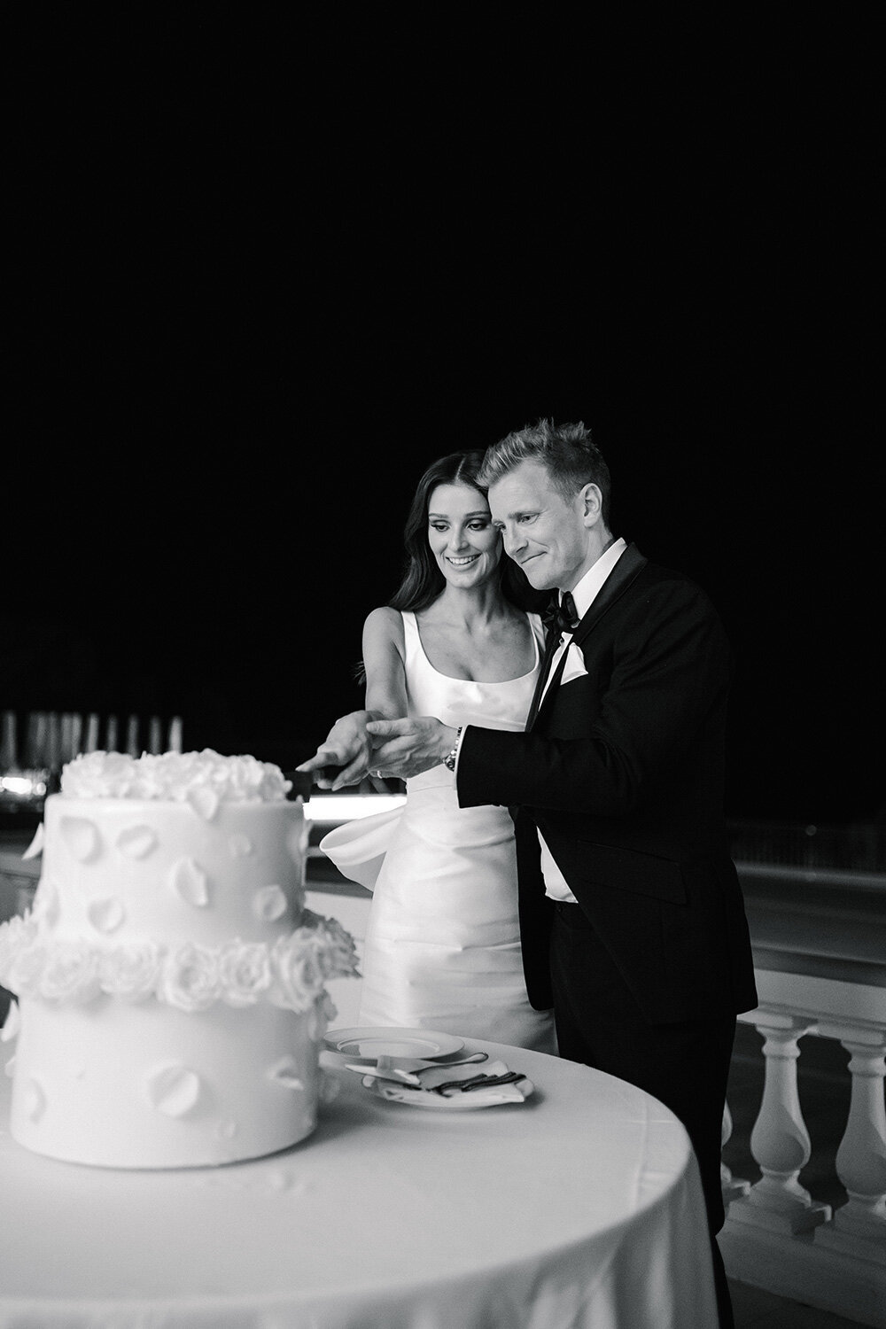classic black and white wedding photo of couple cutting wedding cake