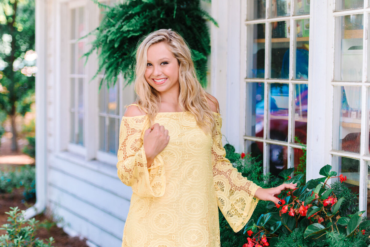 Senior girl in bright yellow lace dress posing near tropical greenery and Charleston palms