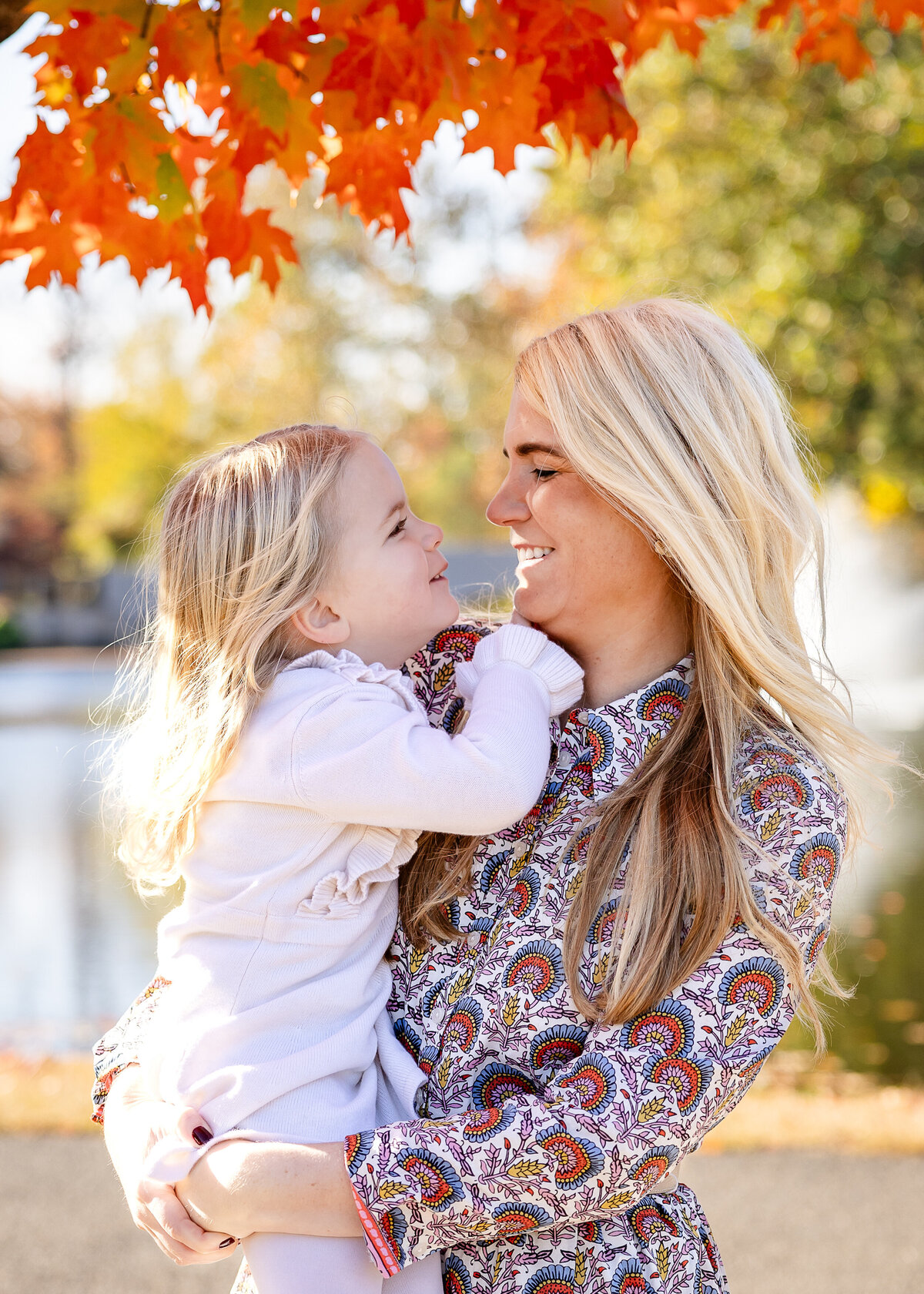 Lifestyle photo of mother hugging and smiling at daughter at an Essex County, New Jersey park in the fall.
