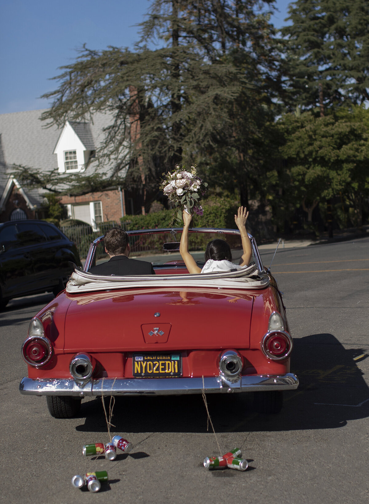 a photo of a bride and groom in a red classic car driving off after the the ceremony