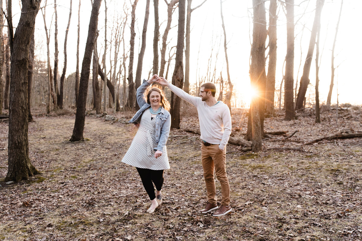 guy twirls girl in woods at sunset