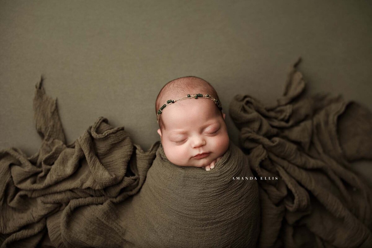 Dark moody portrait of newborn in brown sheets