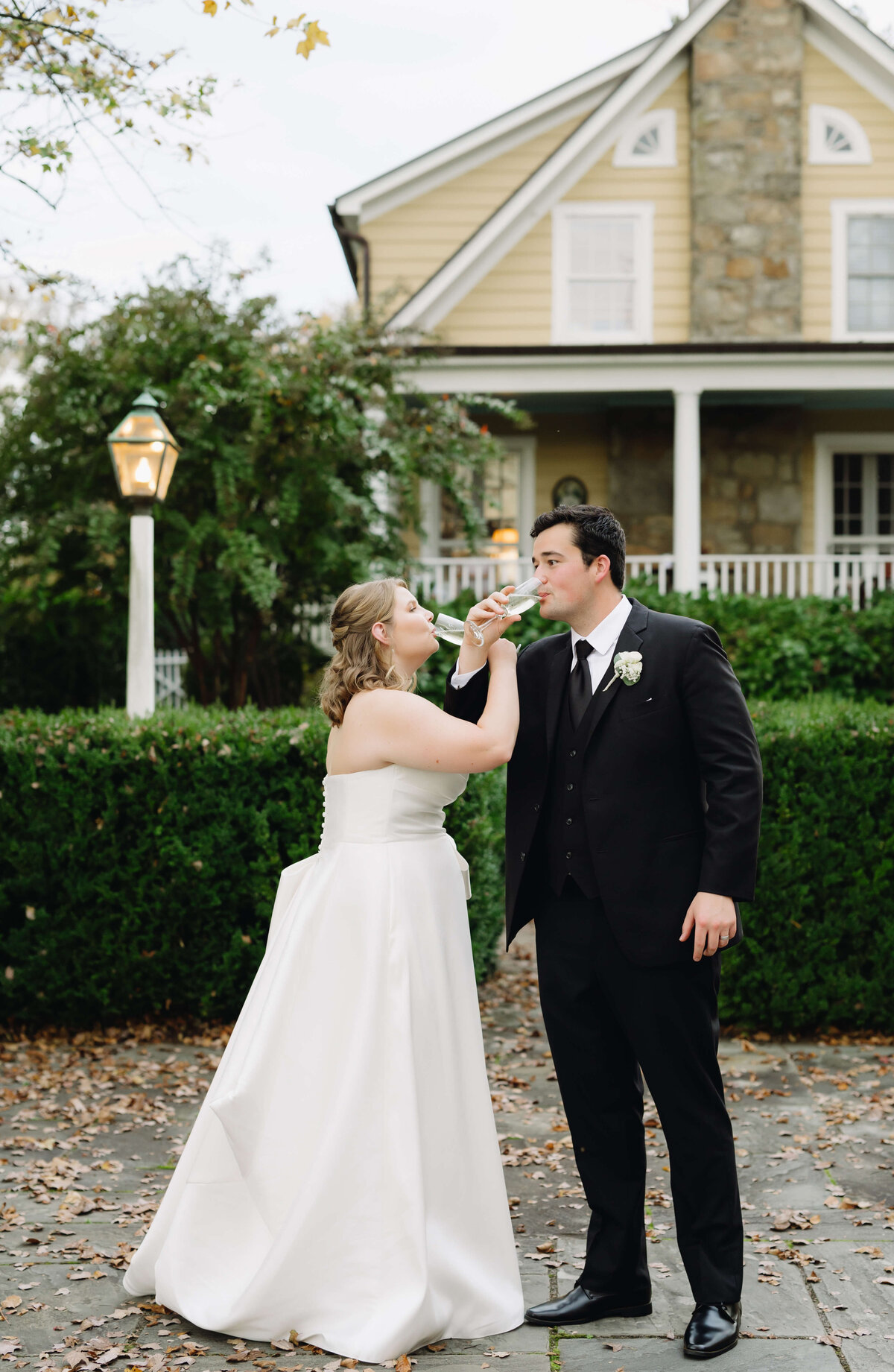 Virginia wedding photographer captures bride and groom sharing a glass of champagne together outside of their Richmond wedding venues front lawn