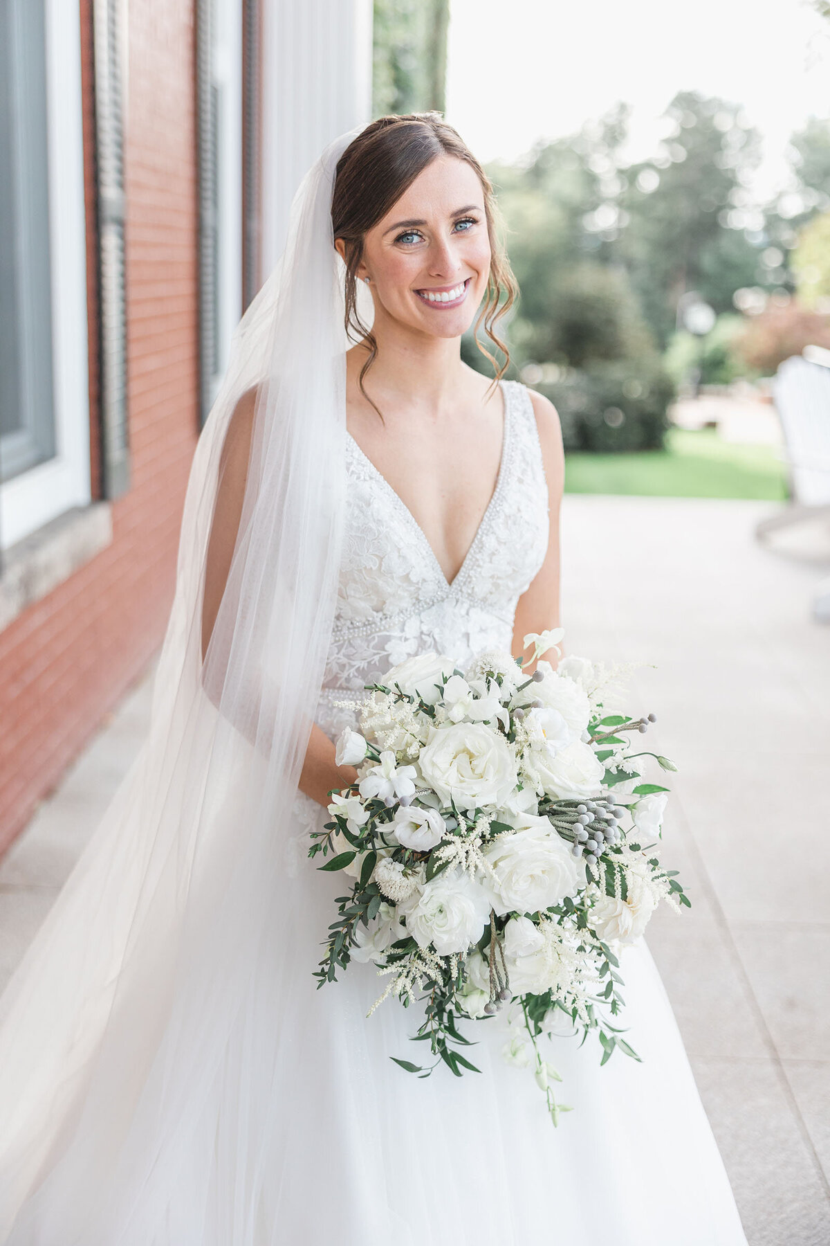 A bride holding her wedding flowers with a long soft veil