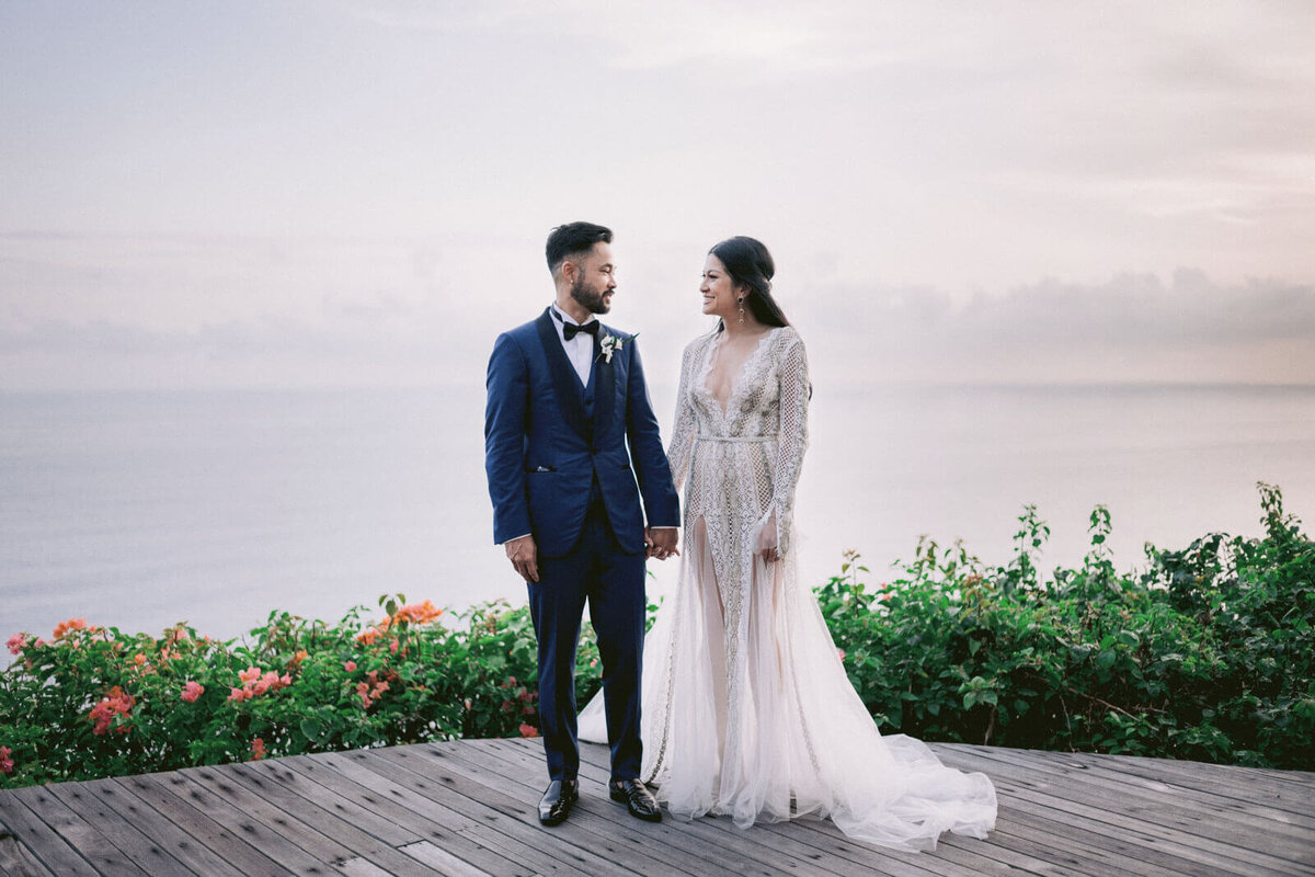 The bride and groom are looking at each other with the ocean in the background in Khayangan Estate, Indonesia. Image by Jenny Fu Studio