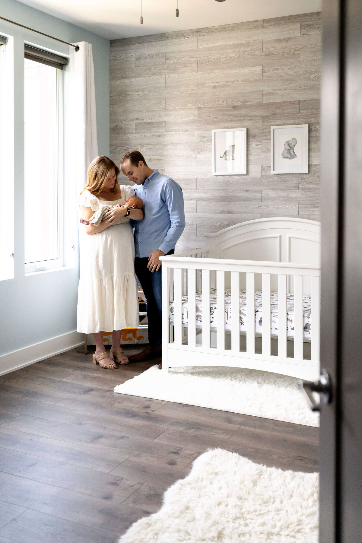 Parents standing in nursery with newborn boy