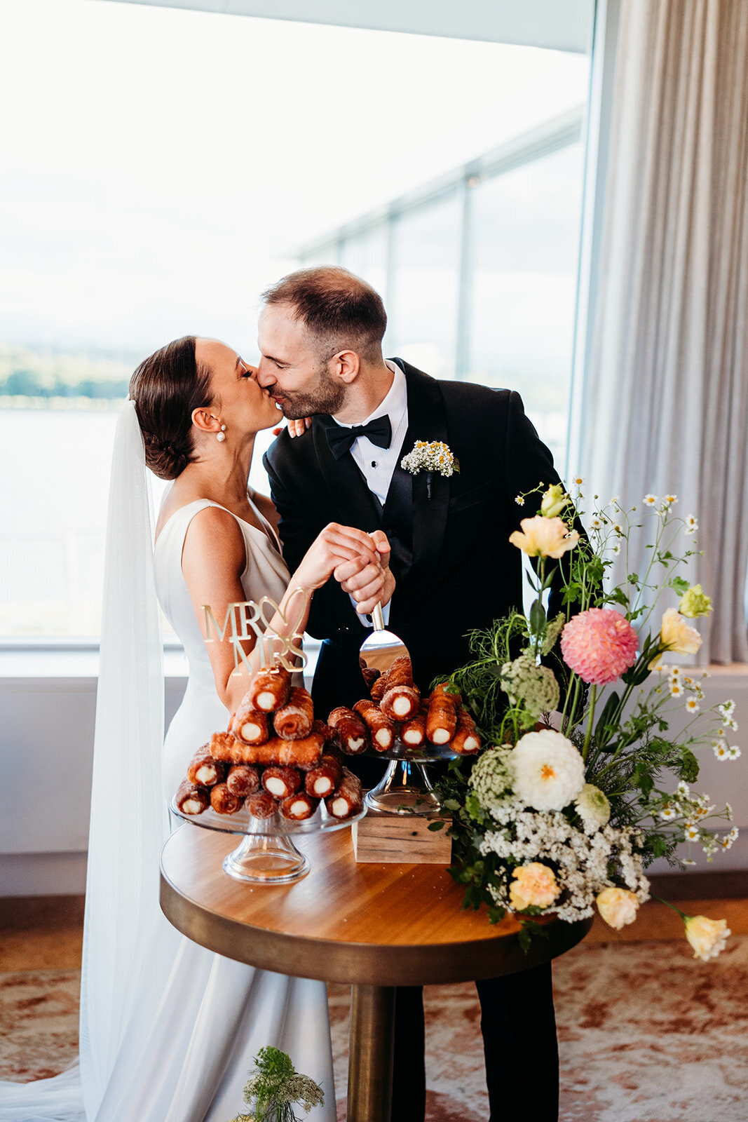 Bride and groom kiss after cutting their 'cake' which was actually a delicious Italian cannoli tower!