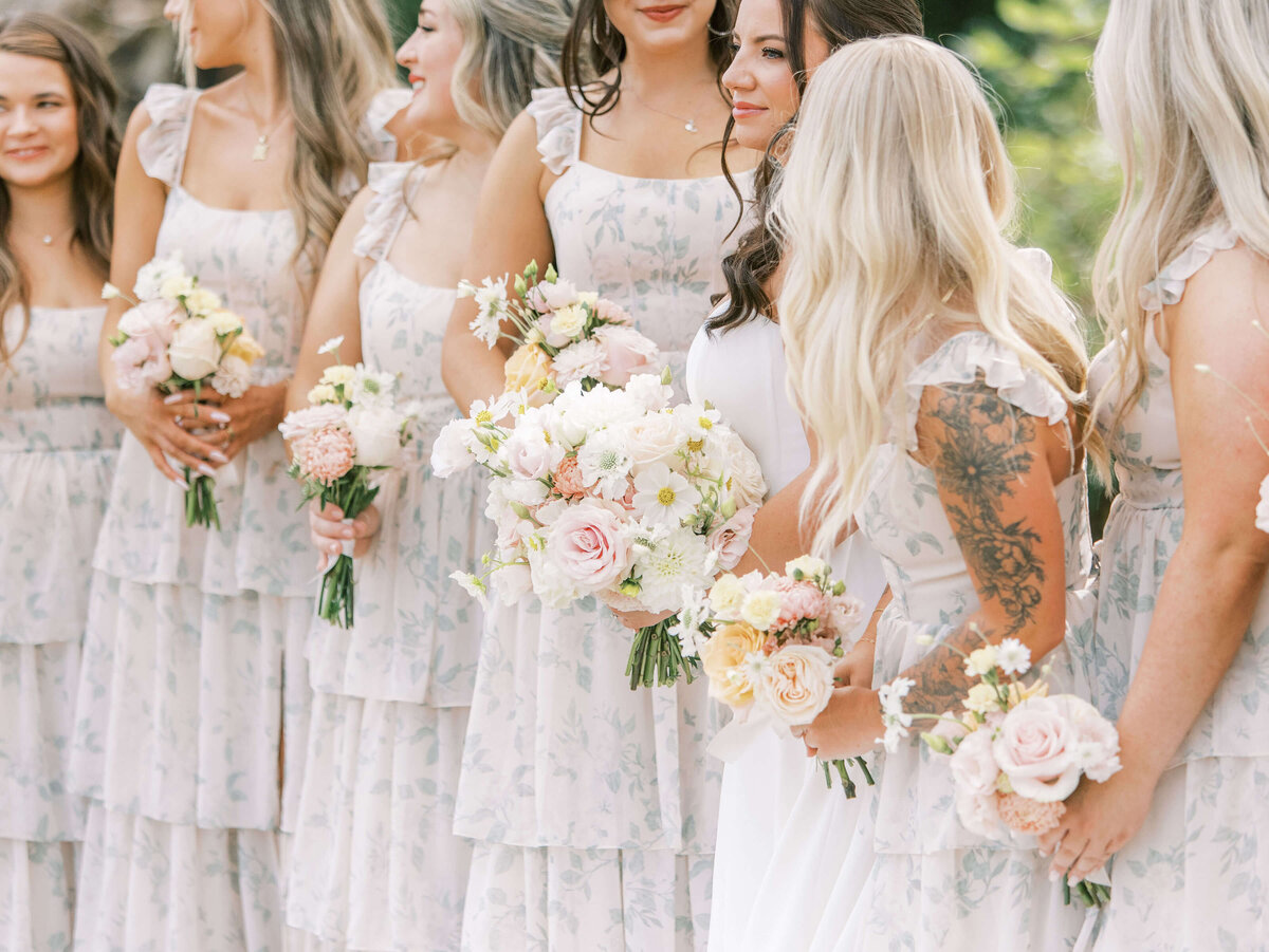 The bridal party stands outdoors and holds their flower bouquets at a luxury backyard wedding in Oregon.