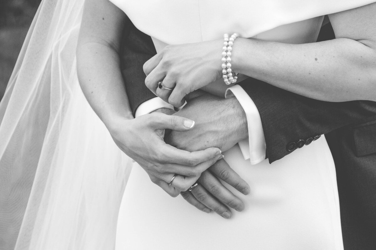 Black and white Ottawa wedding photography showing a bride and groom's hands intertwined  taken  outside on the Chateau Laurier terrace