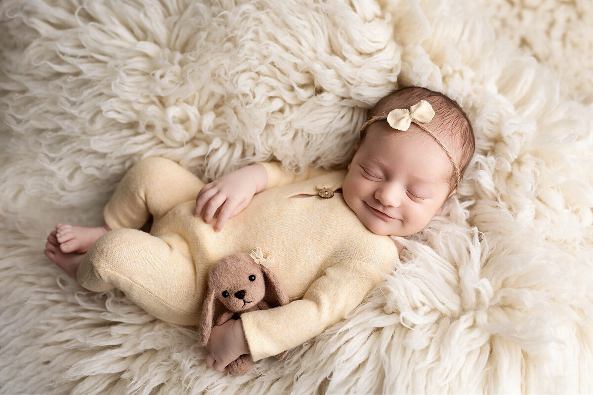 Newborn baby boy wrapped in a tan colored knit wrap with a matching bonnet.