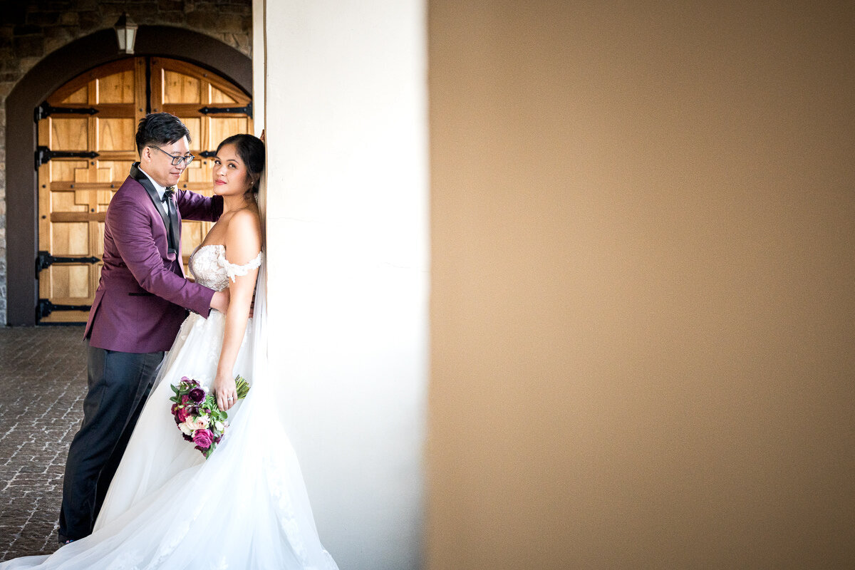 The bride stands confidently beside the groom at Casa Real, her meaningful stare capturing the camera's attention while the groom lovingly focuses on her, creating a striking and emotional wedding portrait.