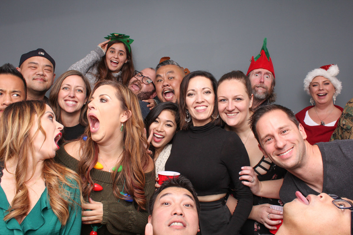 Big group of employees squeeze in for a group photo in a photo booth