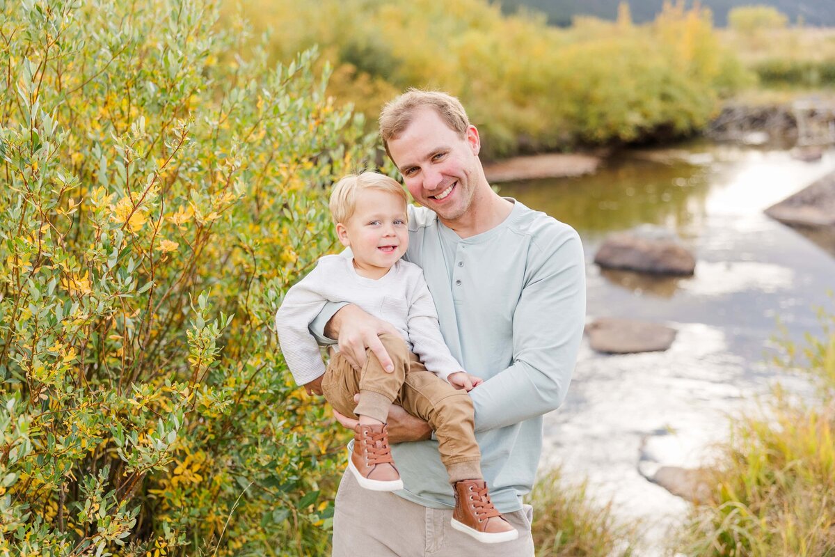 Dad holds son in arms with river behind