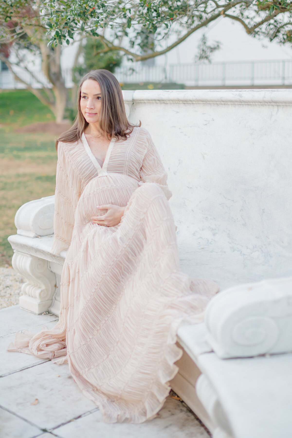 a pregnant woman sits on a beach at a park, captured by Connecticut Maternity Photographer Deborah Jossick