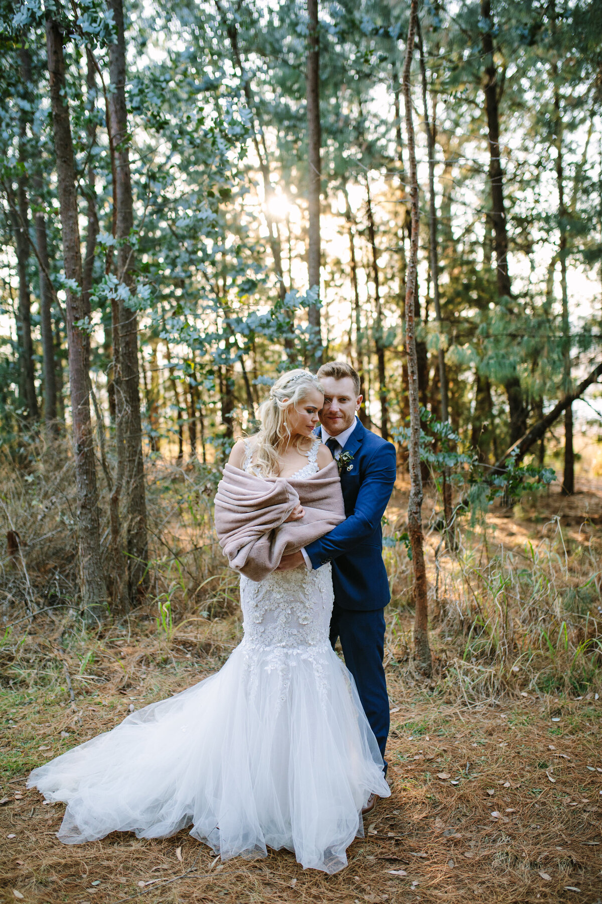 The groom wraps his arms around the bride while their foreheads gently touch. 