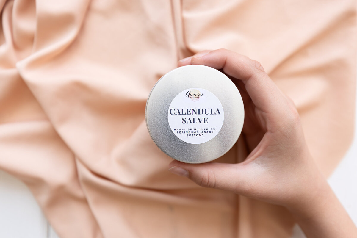 Hands holding a container of calendula salve