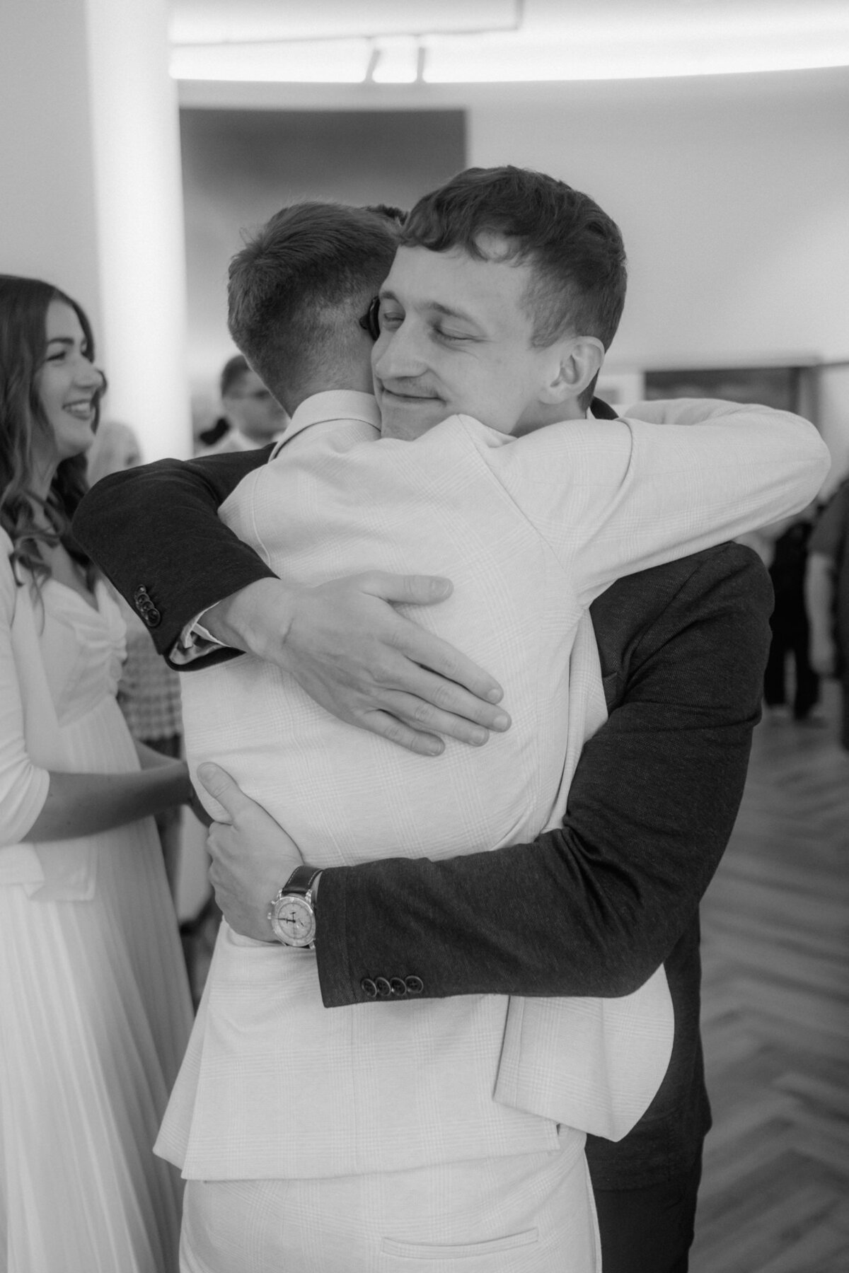 During congratulations the groom hugs his friend - candid wedding moment.
