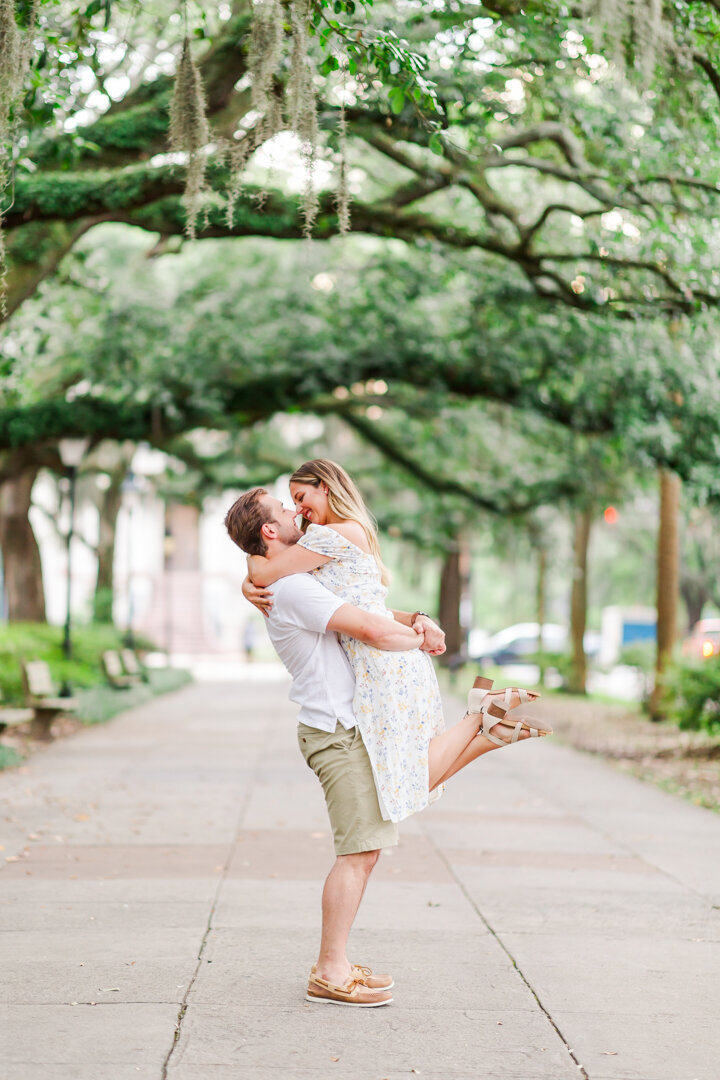 A couple embraces each other on a sidewalk in a park. Captured by Arkansas Wedding Photographer Photography by Karla