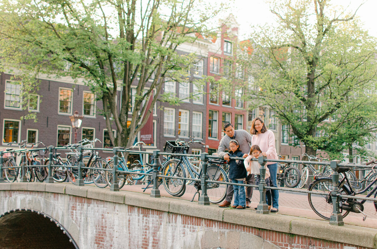 Family standing on canal bridge in Amsterdam at sunset