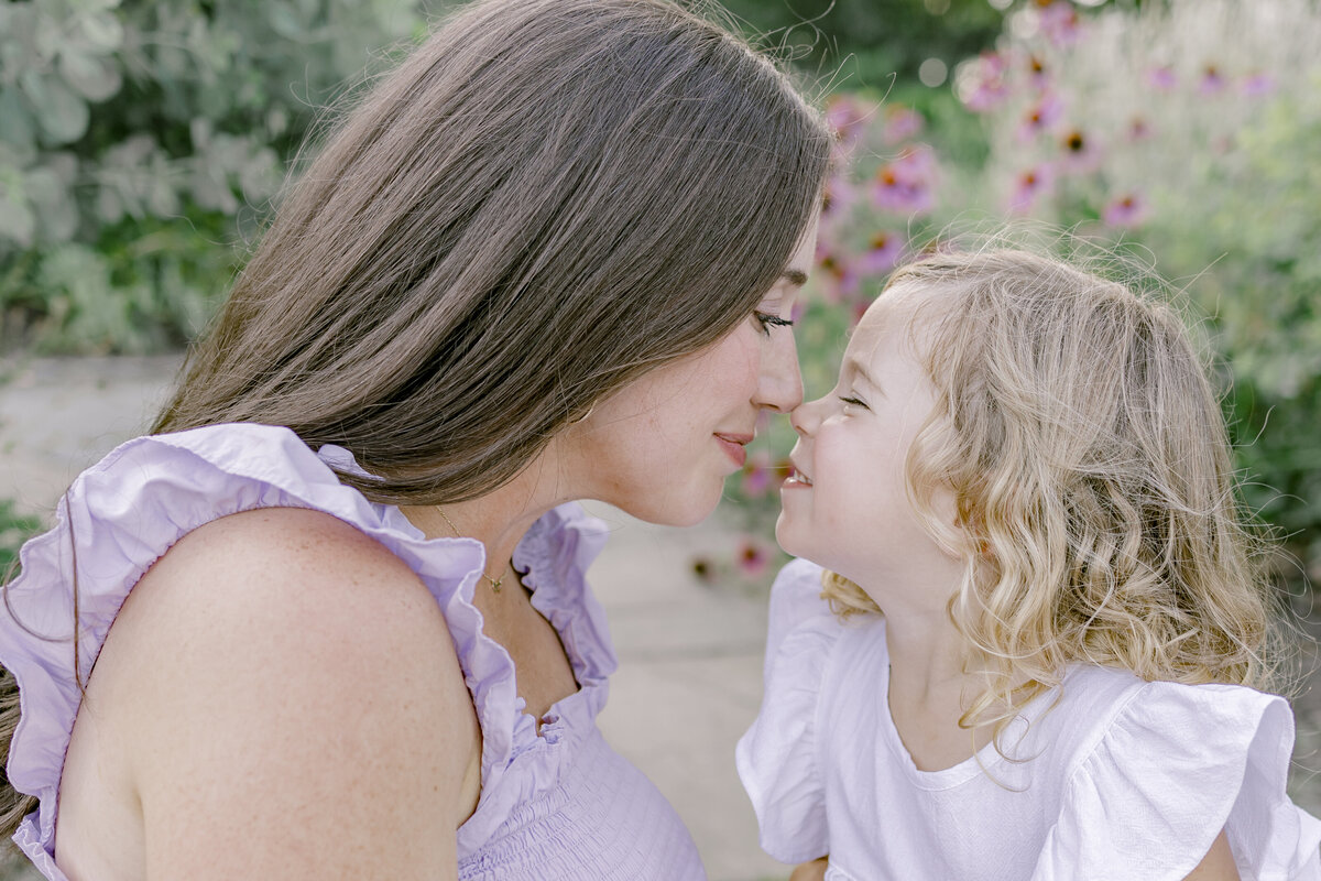 Mother and young daughter looking at each other nose to nose