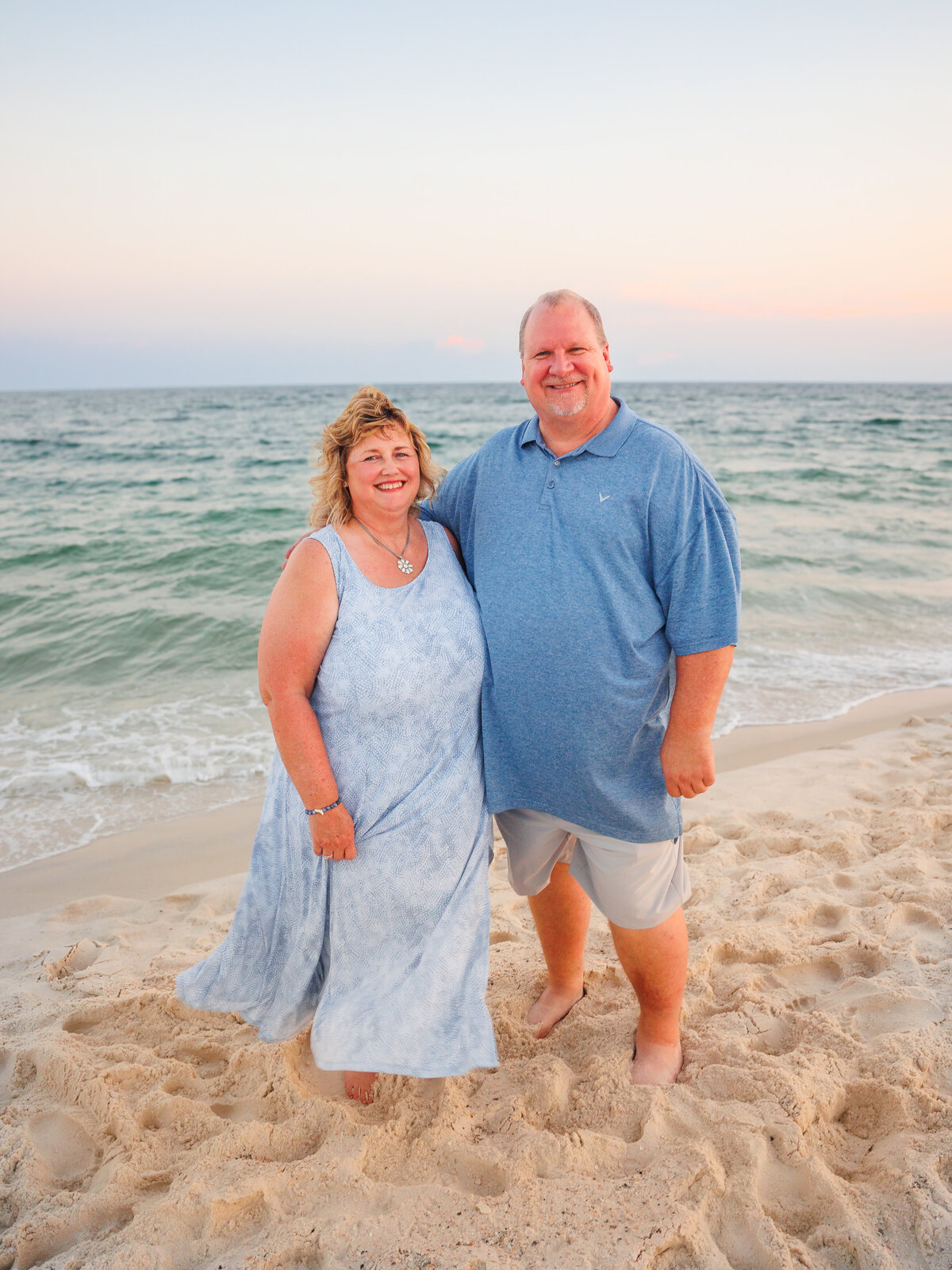 Grandparents pose in front of waves during golden hour
