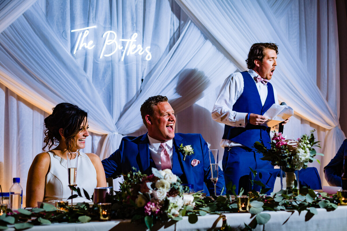 One of the top wedding photos of 2020. Taken by Adore Wedding Photography- Toledo, Ohio Wedding Photographers. This photo is of a bride and groom laughing during the best mans speech
