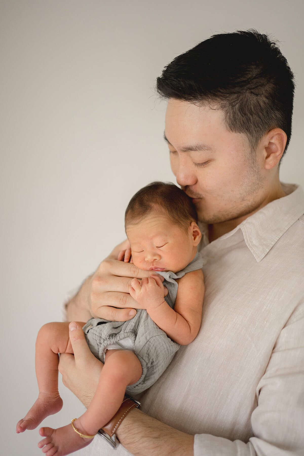 asian dad snuggling with newborn baby in their nursery, captured by maternity photographer hikari lifestyle photography.