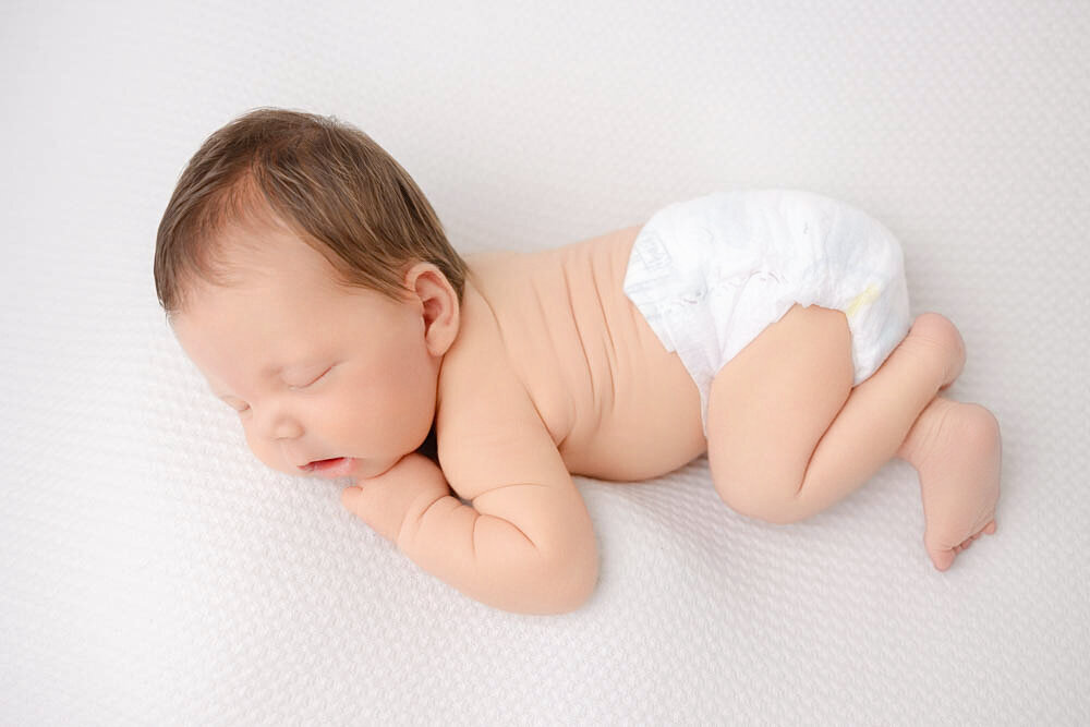 Sleeping newborn baby boy lying face down in just a diaper.
