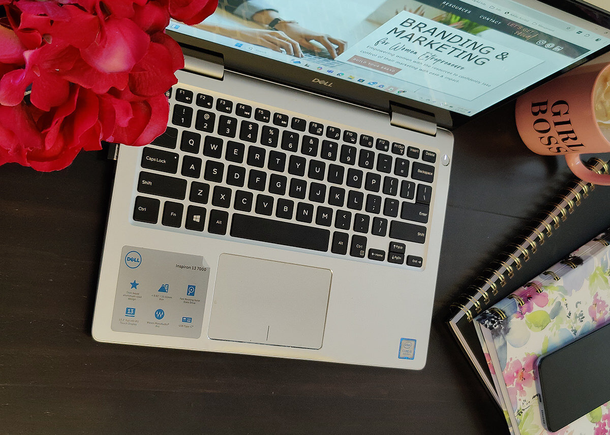 laptop on desk with pink flower, girl boss coffee mug and notebooks