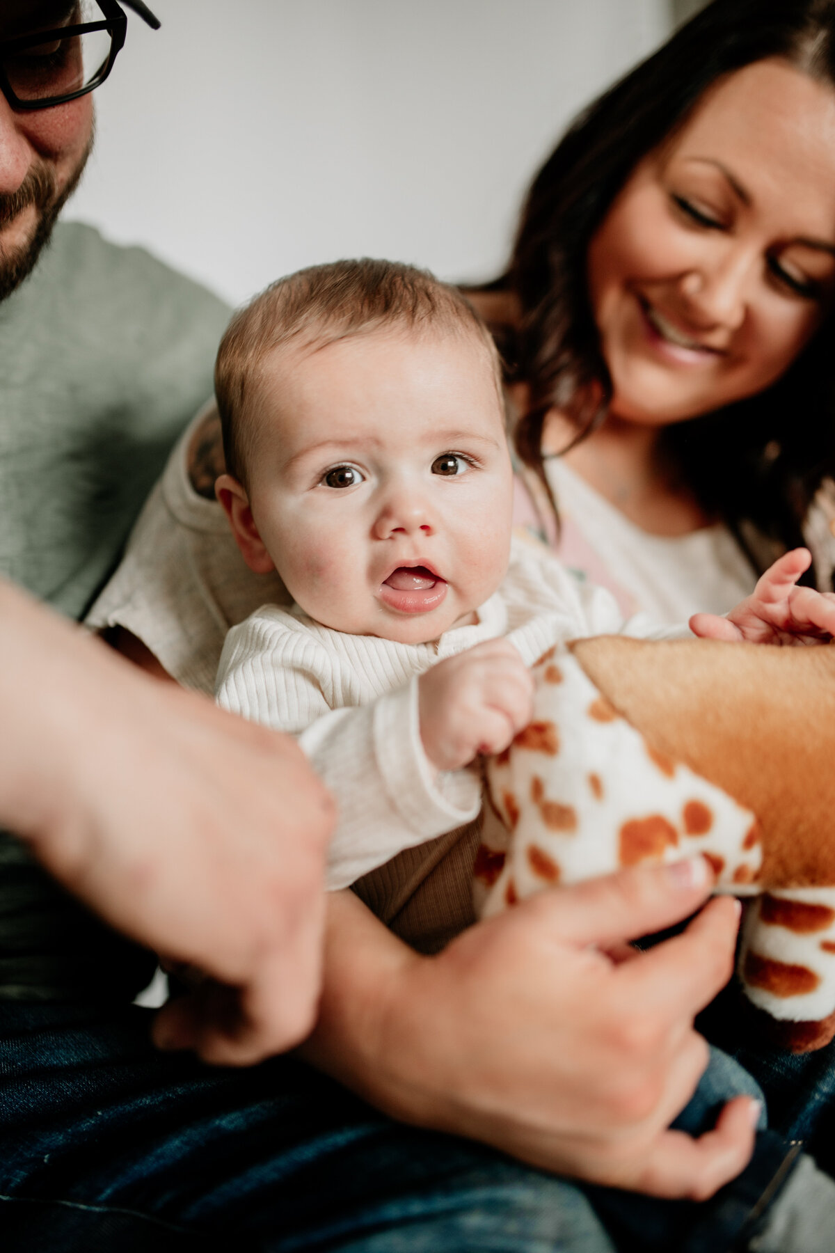 A family of three snuggles up on their couch during six month milestone photos.