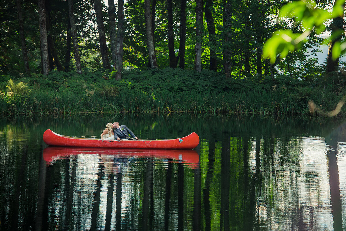 bride and groom kissing in canoe