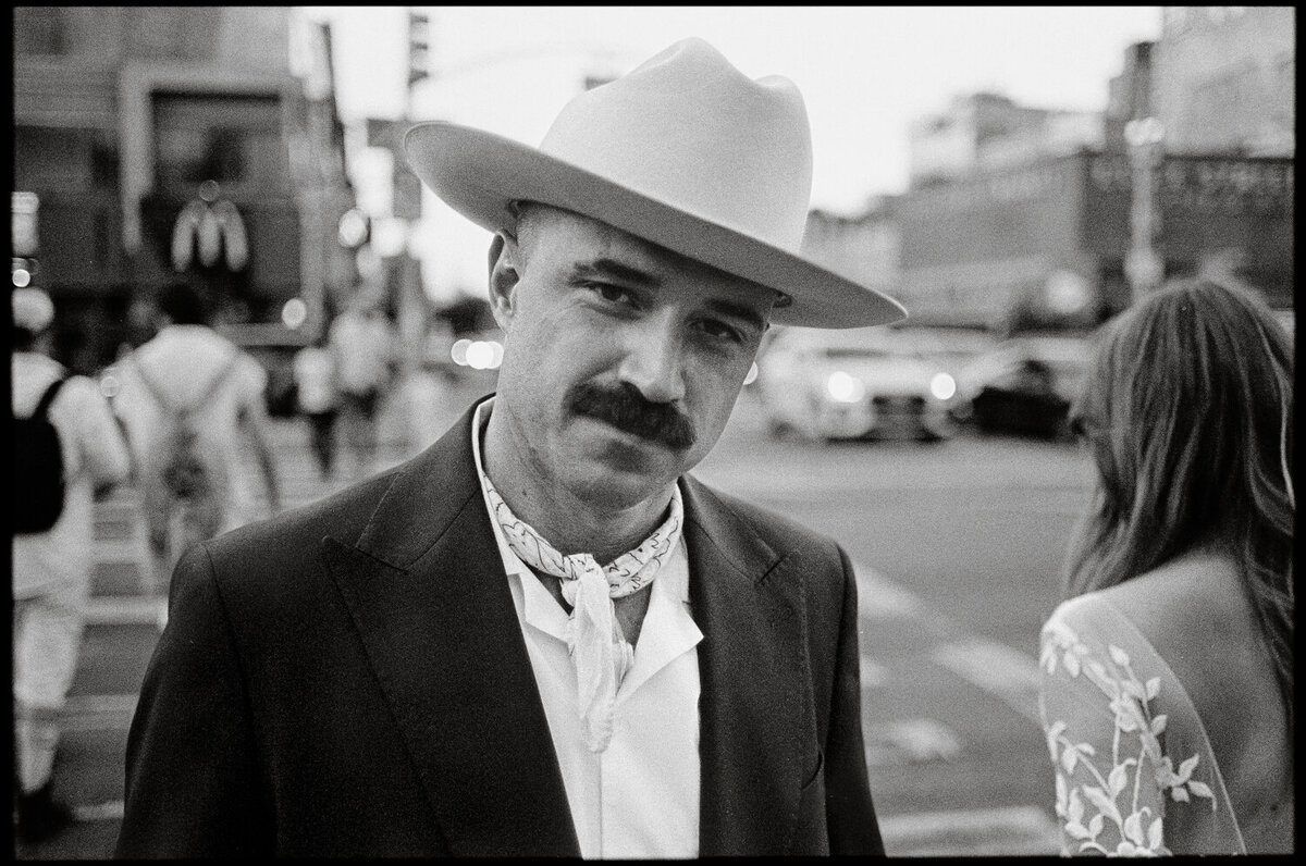Black and white film photo of a groom in a western hat in new york city 