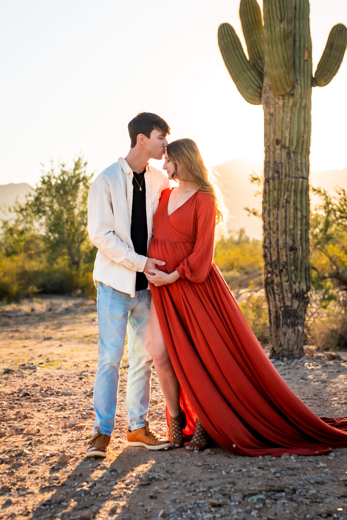 portrait of husband kissing pregnant wife gently on her forehead. Photographed at sunset by Cactus & Pine Photography