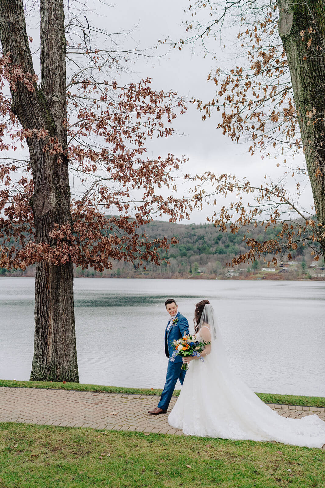 Couple walking along Lake Otsego on their wedding day