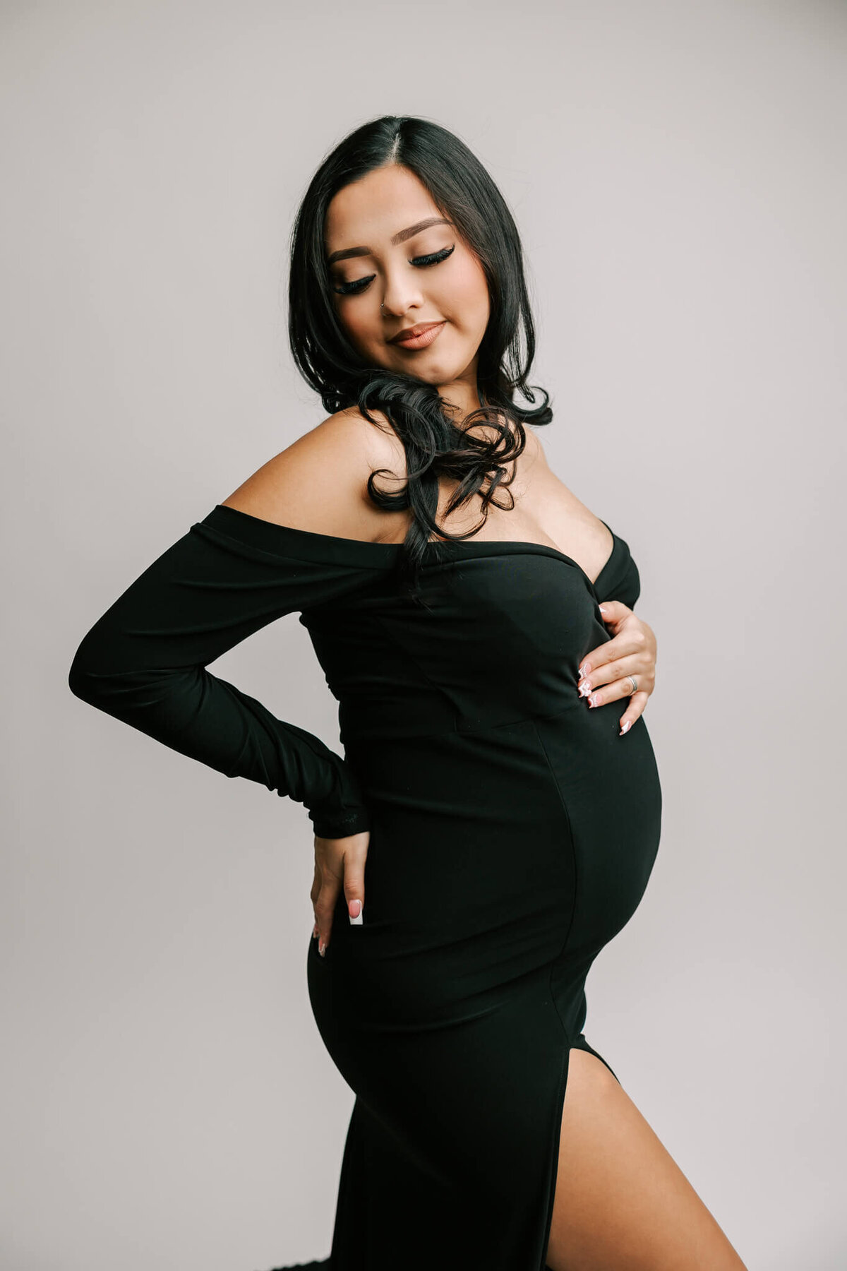 fine art maternity phtography by Ann Marshall featuring mom wearing a black dress and looking over her shoulder