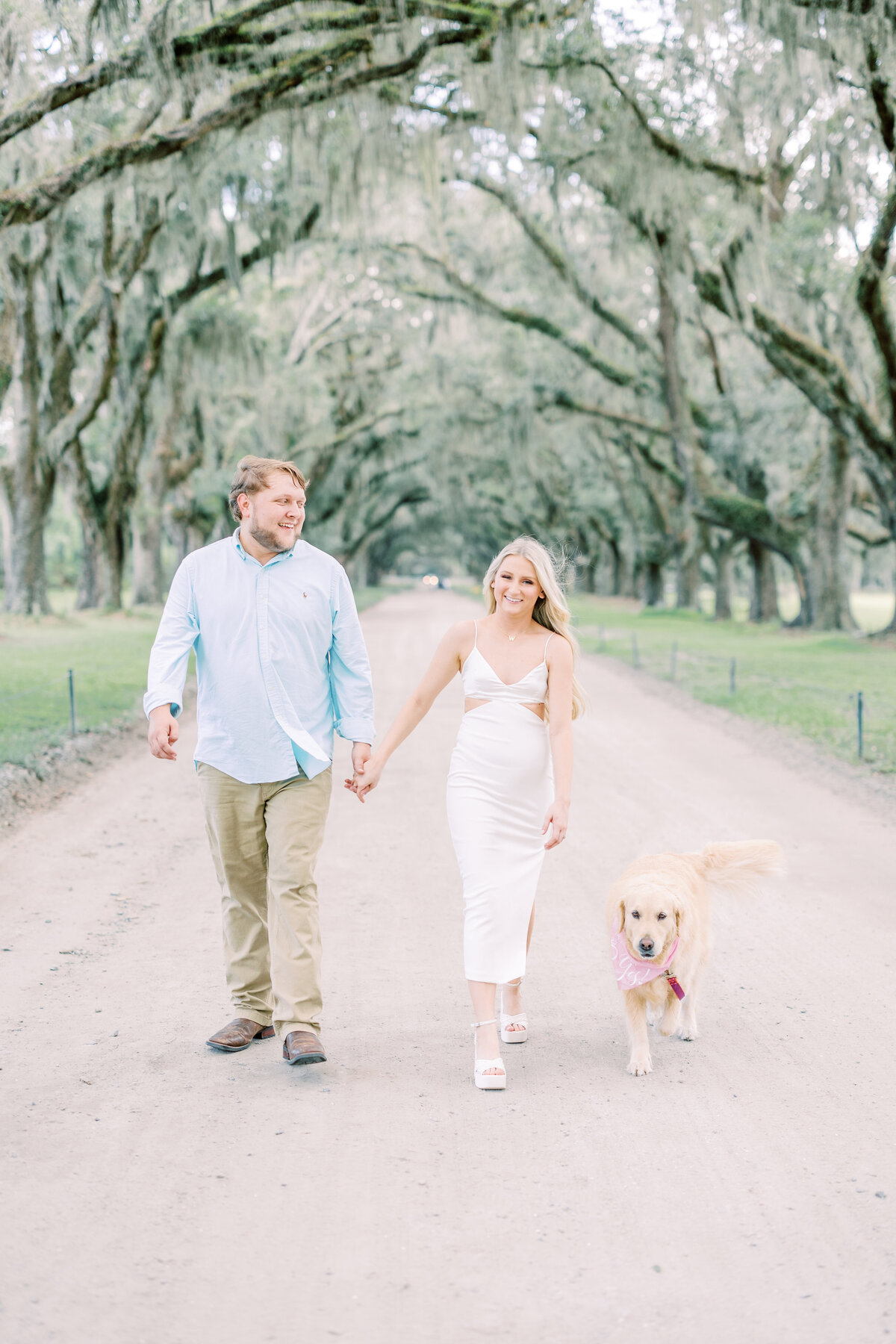 engaged couple with their dog in a tree-lined street