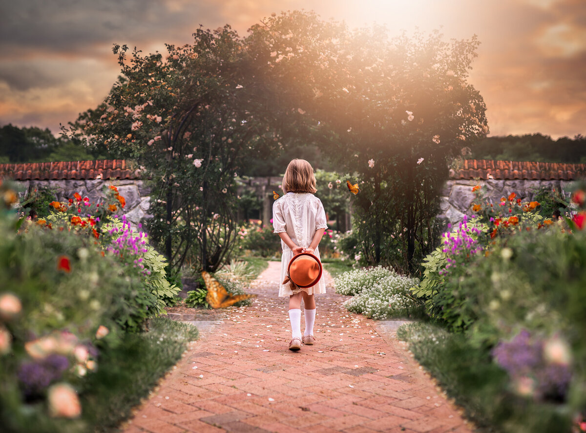 A little girl dressed in victorian era clothes walking through a garden while butterflies fly around
